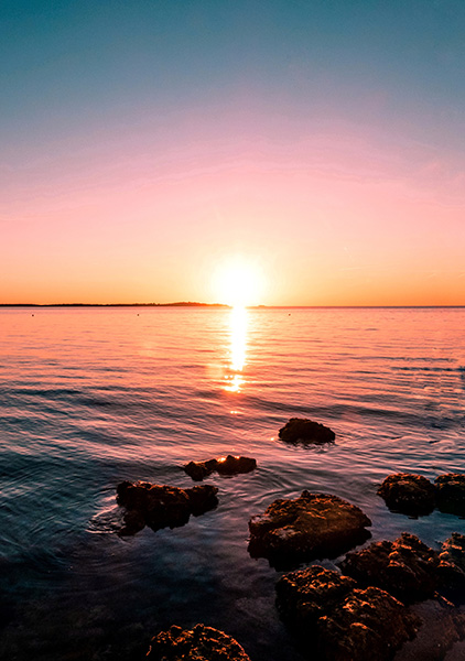 Sun setting on the horizon over body of water