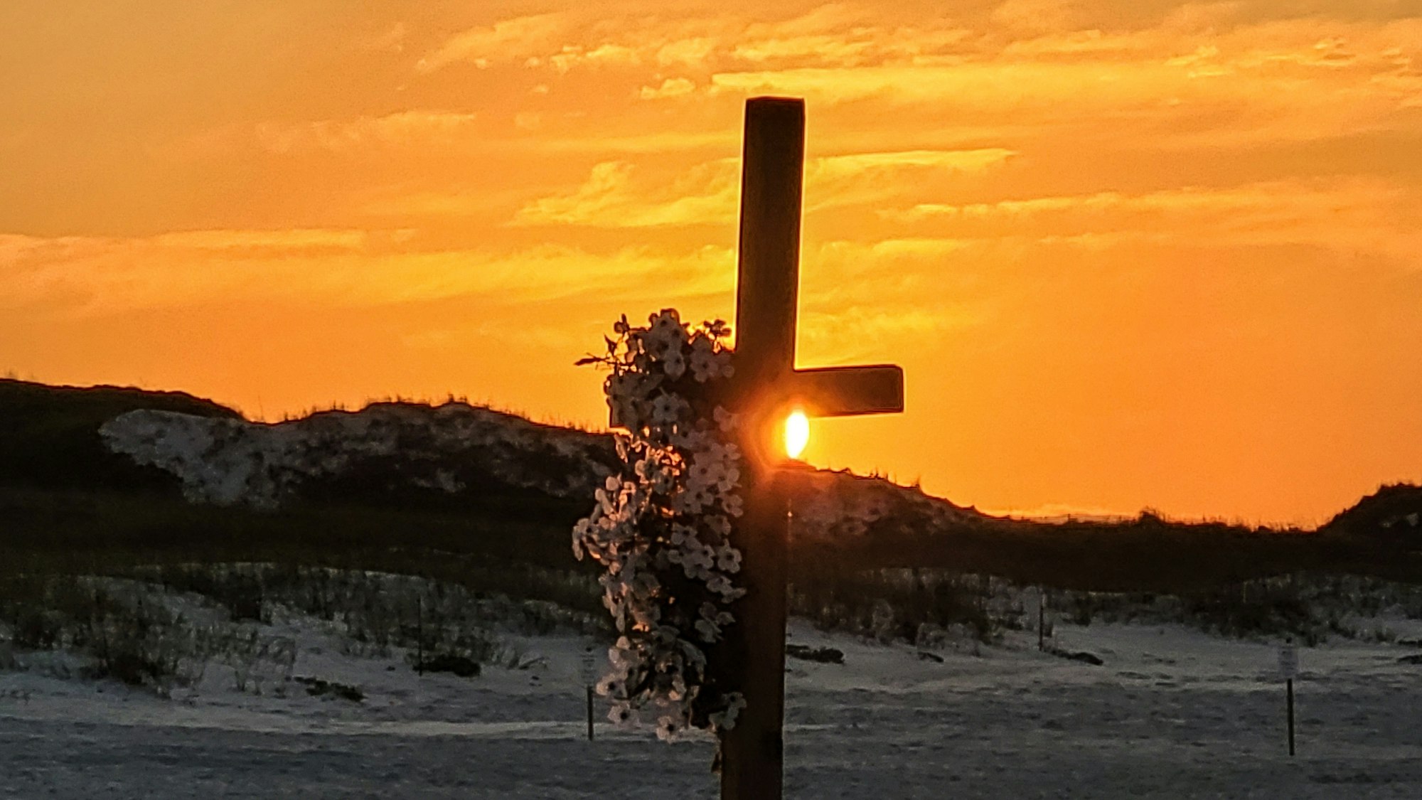 The wooden cross with flowers symbolizes Christ risen from the dead on Easter Sunday.