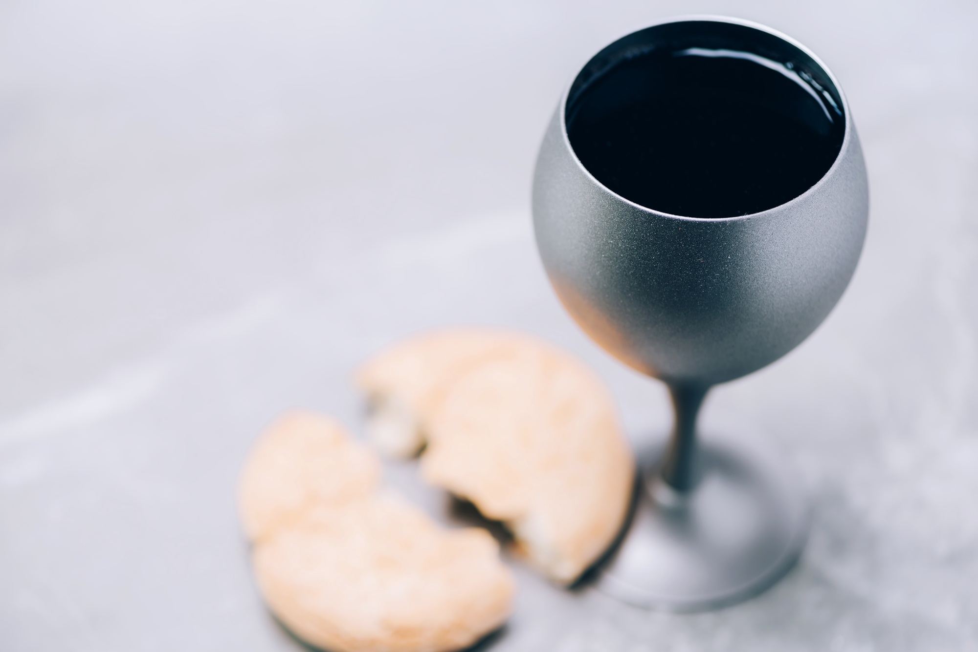 Communion still life. Unleavened bread, chalice of wine on grey background. Christian communion